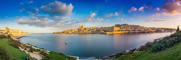 La Valette, Malte - Vue panoramique sur l'ancienne ville de La Valette et Sliema au lever du soleil depuis l'île de Manoel au printemps avec voilier, ciel bleu, beaux nuages et herbe verte — Photo