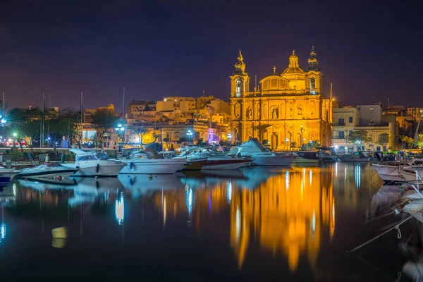 Msida, Malta - La hermosa iglesia parroquial de Msida con yates y barcos y reflexión sobre el agua por la noche — Foto de Stock