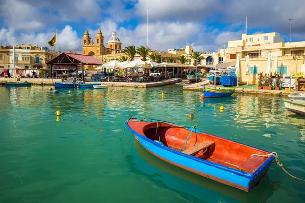 MARSAXLOKK, Malta - geleneksel renkli Malta Luzzu fisherboat eski Marsaxlokk Köyü turkuaz deniz su, mavi gökyüzü ve palmiye ağaçlarıyla bir yaz gününde — Stok fotoğraf