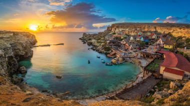 Il-Mellieha, Malta-inanılmaz renkli bulutlar ve gökyüzü günbatımı geleneksel Luzzu teknelerle çapa Koyu'ndaki ünlü Temel Reis Köyü manzarası manzaraya