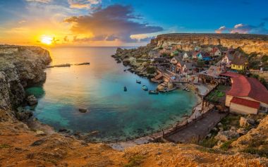 Il-Mellieha, Malta-inanılmaz renkli bulutlar ve gökyüzü günbatımı geleneksel Luzzu teknelerle çapa Koyu'ndaki ünlü Temel Reis Köyü manzarası manzaraya
