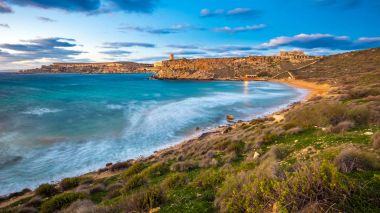 Mgarr, Malta - ünlü Ghajn Tuffieha bay uzun pozlama mavi bir saatte güzel gökyüzü ve bulutlar ile vurdu