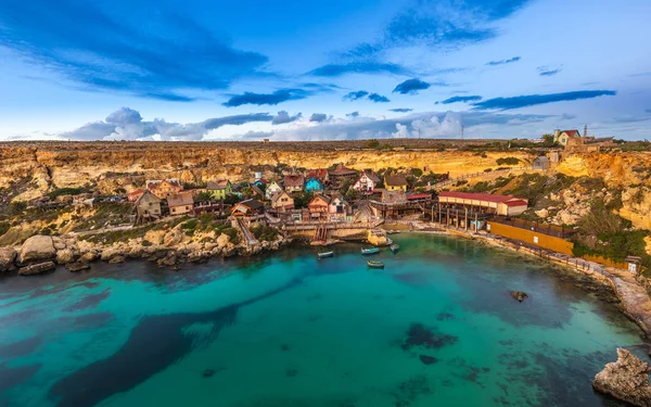 Mellieha, Malta - El famoso Popeye Village en Anchor Bay al atardecer con increíbles nubes de colores y cielo — Foto de Stock