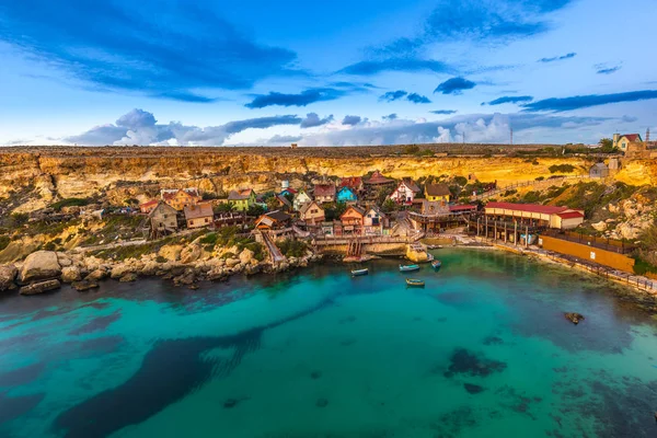 Mellieha, Malta - El famoso Popeye Village en Anchor Bay al atardecer con increíbles nubes de colores y cielo — Foto de Stock