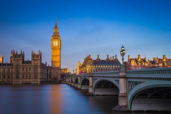 London, England - The beautiful Big Ben and Houses of Parliament at sunrise with clear blue sky and red double decker bus — Stock Photo, Image