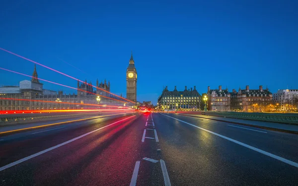 Londyn, Anglia - Big Bena i Houses of Parliament, pochodzi z połowy Westminster Bridge o zmierzchu z światła samochody i autobusy przechodzi — Zdjęcie stockowe