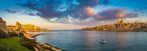 在春天的时候用帆船、 蓝蓝的天空、 美丽的云彩和绿草从曼岛拍摄的瓦莱塔，马耳他-瓦莱塔古代城市和斯利玛日出时的全景的天际线景观 — 图库照片