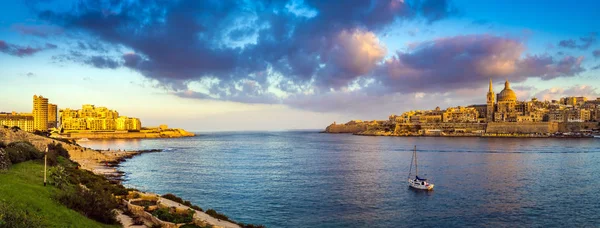 La Valette, Malte - Vue panoramique sur l'ancienne ville de La Valette et Sliema au lever du soleil depuis l'île de Manoel au printemps avec voilier, ciel bleu, beaux nuages et herbe verte — Photo