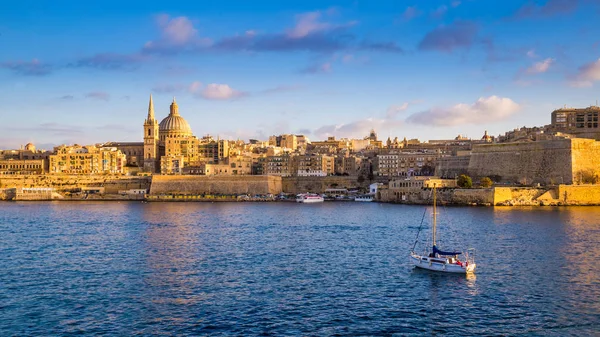 Valletta, Malta - panoramatický pohled katedrála svatého Pavla a starobylé zdi Valletty s plachtou lodí v noci — Stock fotografie