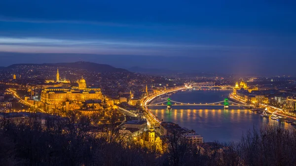 Budapest, Hongarije - de mooi verlichte historisch Koninklijk Paleis of het kasteel Buda met Szechenyi Chain Bridge, Parlement en Matthias kerk en de Buda heuvels op blauwe uur — Stockfoto