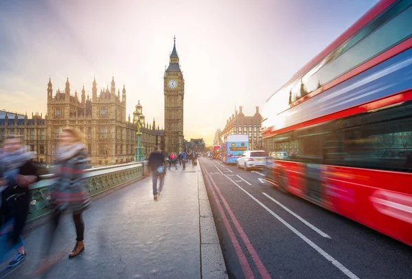 Лондон, Англия - Знаменитый Биг-Бен и здание парламента со знаменитым красным двухэтажным автобусом и туристами в движении по Вестминстерскому мосту на закате — стоковое фото