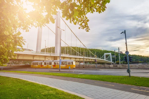 Budapešť, Maďarsko - tradiční žluté tramvaje procházející pod Alžbětin most na Dunaji s Gellért Hill na pozadí — Stock fotografie