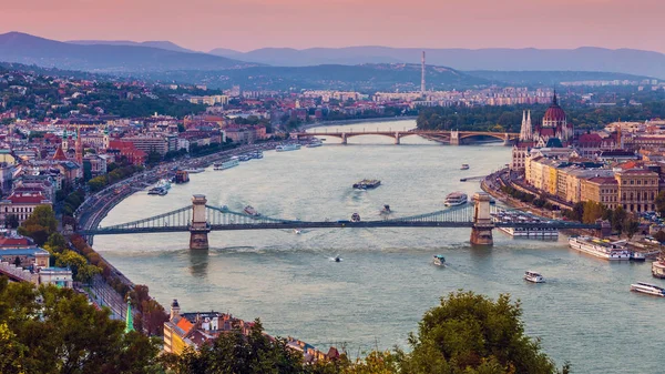 Budapest, Magyarország - panorámás skyline view a naplemente, a híres Széchenyi Lánchíd, Margit híd, Margit-sziget és Magyarország Parlament, a Budai hegyek a háttérben színes égbolt — Stock Fotó