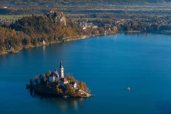 Bled, Eslovenia - Salida del sol en el lago Bled tomada desde el mirador de Osojnica con el barco tradicional Pletna y el castillo de Bled al fondo en otoño — Foto de Stock