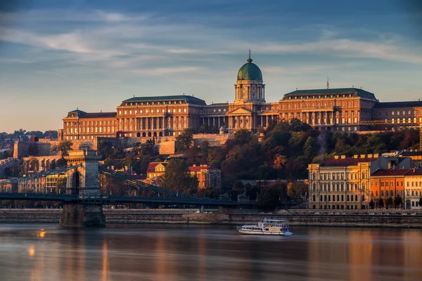 Будапешт, Венгрия - золотой рассвет со стороны Буды с королевским дворцом Буда, Цепным мостом и обзорной лодкой на Дунае — стоковое фото