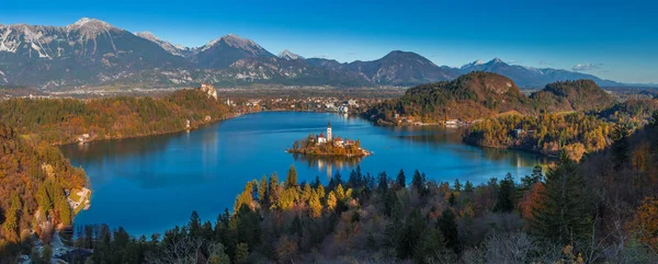 Bled, Szlovénia - panorámás skyline view hozott Ojstrica szempontból a híres kegytemplom, Nagyboldogasszony Mária, hagyományos túltengés csónakok és Bled kastélyára háttér őszi Bledi-tó — Stock Fotó