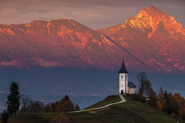 Jamnik, Slovenia - Bellissimo tramonto dorato nella chiesa di Jamnik St. Primoz con le Alpi Giulie sullo sfondo alla luce del sole dorata — Foto Stock