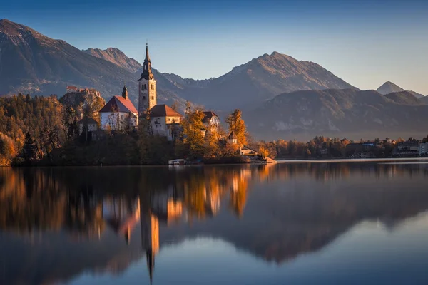 Bled, Szlovénia - gyönyörű őszi sunrise-tó Bled híres zarándok templom, a Nagyboldogasszony Mária, a Bledi várra és a Júliai-Alpokra a háttérben — Stock Fotó