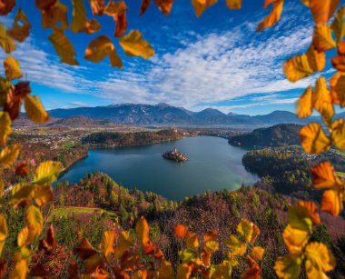 Bled, Slovenya - Lake Bled alınan ünlü hac Kilisesi Maria varsayım, geleneksel Pletna tekneleri ve Bled Castle Ojstrica bakış açısıyla arka plan, sonbahar görünümünü panoramik manzarası. Sonbahar yaprakları ile çerçeveli