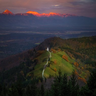 Jamnik, Slovenya - güzel altın günbatımı hava görünümünü Jamnik St. Primoz Kilisesi. Julian Alps, arka planda güneş ışığı