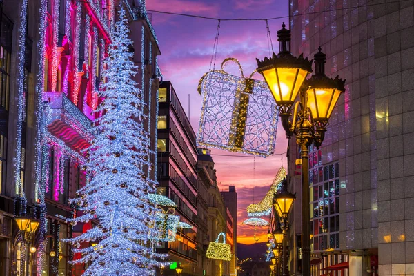 Budapest, Hungary - Beautiful shopping street scene with lamp post, glowing Christmas tree and lights and decorations and colorful sunset sky in central Budapest