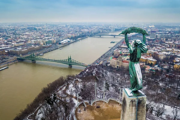ブダペスト, ハンガリー - 曇った冬の日ゲッレールトの丘から撮影したバック グラウンドで自由の女神像、自由の橋とドナウ川と雪のブダペストの空中パノラマ ビュー — ストック写真
