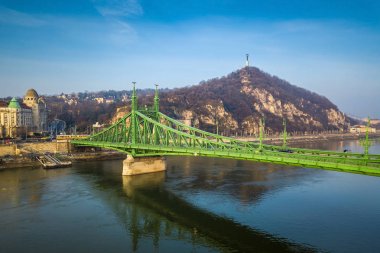 Budapest, Hungary - Beautiful Liberty Bridge (Szabadsag Hid) and traditional yellow Hungarian tram on a busy winter morning with Gellert Hill, Citadella and, Statue of Liberty at background clipart