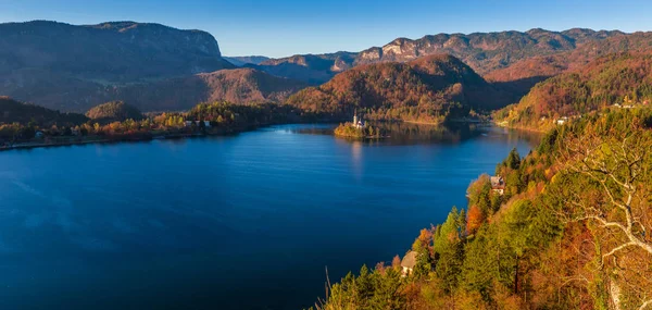 Bled, Szlovénia - panorámás skyline view meleg őszi lombozat a Bledi-tó és a híres zarándoktemplom Maria feltételezés az és az Alpok, a háttérben — Stock Fotó