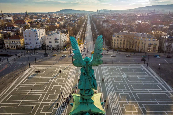 Будапешт - ангел скульптура ззаду на вершині площі Героїв на захід сонця з вулиці Андраші та skyline Будапешта на тлі — стокове фото