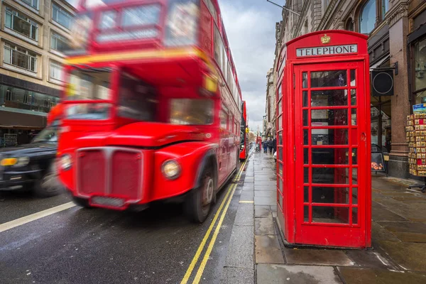 London, Anglia - ikonikus elmosódik a londoni fekete taxi és vintage piros emeletes busz útközben Londonban a központ a hagyományos piros telefonfülke a nappali — Stock Fotó