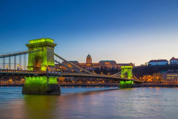 布达佩斯, 匈牙利-绿色光照亮塞切尼链桥在河多瑙河和布达城堡皇家宫殿在蓝色小时以清楚的蓝天 — 图库照片