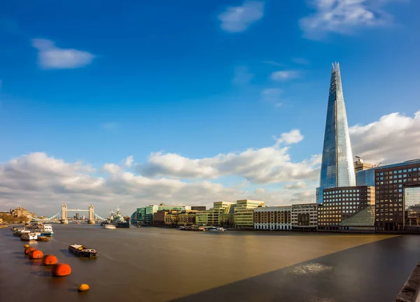Londres, Inglaterra - The Shard, el rascacielos más alto de Londres con el emblemático Tower Bridge al fondo en una tarde soleada con cielo azul y nubes —  Fotos de Stock