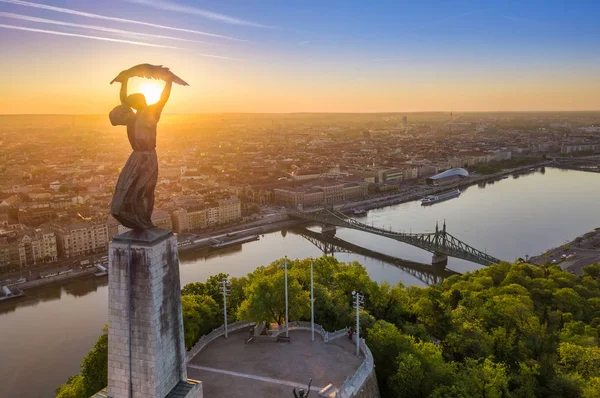 Budapest, Magyarország - Kilátás a gyönyörű Szabadság-szoborra a Szabadság híddal és Budapest városára napkeltekor, tiszta kék égbolttal — Stock Fotó