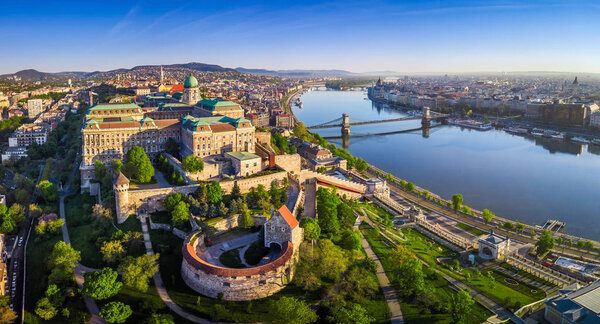 Budapest, Hungary - Aerial panoramic skyline view of Buda Castle Royal Palace with Szechenyi Chain Bridge, St.Stephen's Basilica, Hungarian Parliament and Matthias Church at sunrise with blue sky