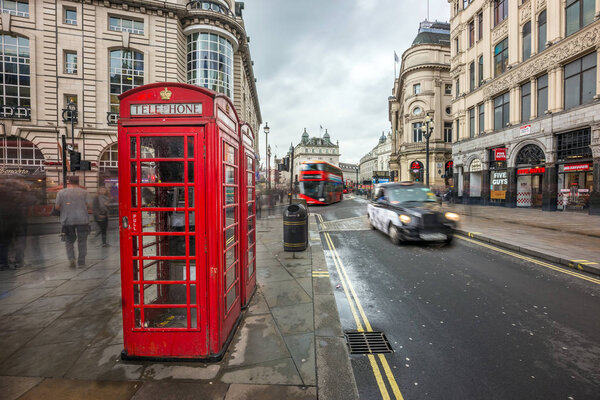 London, England - 15.03.2018: Iconic red telehone box near Piccadilly Circus with red double-decker bus and black taxi on the move