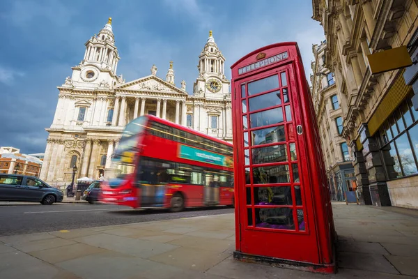 Londres, Inglaterra - Tradicional cabina de teléfono rojo con icónico autobús rojo de dos pisos en movimiento en la Catedral de San Pablo en un día soleado —  Fotos de Stock