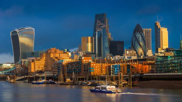 London, England - skyskrapor i Bank, det ledande finansiella distriktet i London på gyllene timmen med sightseeingbåt och färgglada mörk himmel och moln — Stockfoto