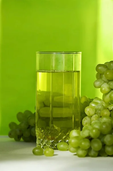 Yellow grape juice and bunches of green grapes