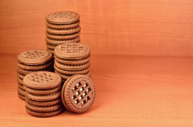 Çikolatalı sandviç bisküvi vanilya krema boşaltmak kahverengi ahşap tablo doldurma ile yuvarlak. Natürmort beyaz krema dolgulu tatlı ve lezzetli Kurabiye.