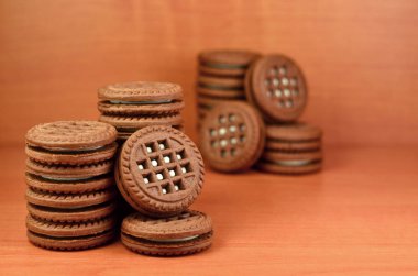 Çikolatalı sandviç bisküvi vanilya krema boşaltmak kahverengi ahşap tablo doldurma ile yuvarlak. Natürmort beyaz krema dolgulu tatlı ve lezzetli Kurabiye.