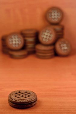 Çikolatalı sandviç bisküvi vanilya krema boşaltmak kahverengi ahşap tablo doldurma ile yuvarlak. Natürmort beyaz krema dolgulu tatlı ve lezzetli Kurabiye.