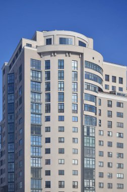 Çok katlı ofis ile lots-in cam pencere bej renk saf mavi gökyüzü bir arka plan üzerinde. Yeni inşa edilen ofis alanı Kiralık