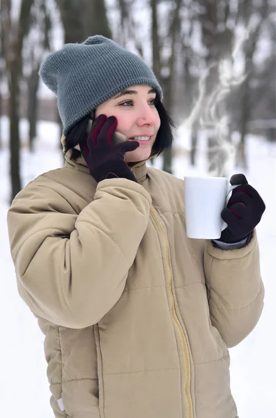 Retrato de inverno de menina com smartphone e xícara de café — Fotografia de Stock