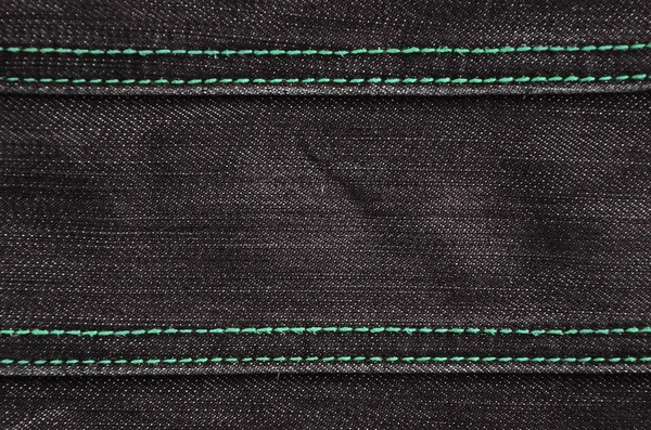 The texture of denim in classic monochrome tone with bright seams of thin fabric. The background image on the production of rigid denim clothing