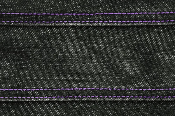 The texture of denim in classic monochrome tone with bright seams of thin fabric. The background image on the production of rigid denim clothing