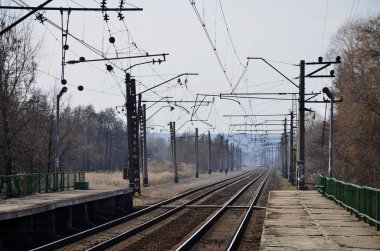 Bir tren istasyonu trenler güneşli bir günde bir çok ağaçlar ve tarlaları arasında bir kentsel yerleşim için beklediğiniz platformları ile. Demiryolu erken Bahar sezonu