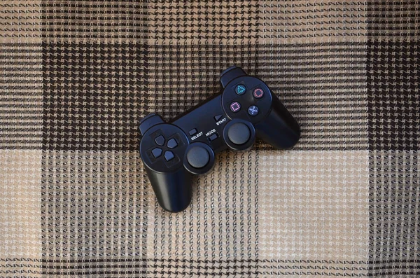 Video game controller lies on a checkered plaid