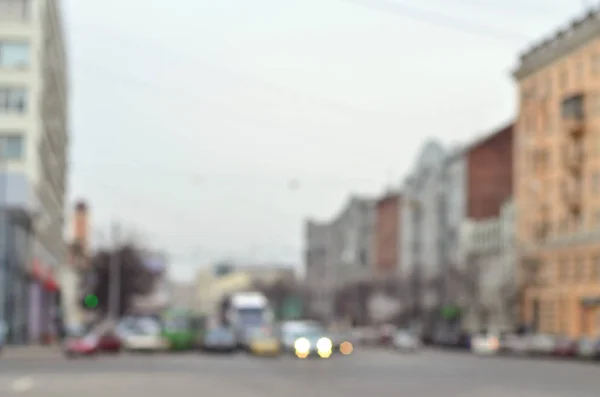 Blurred and defocused landscape with a city road during traffic. A lot of cars drive along the road in the middle of the city in the evening time