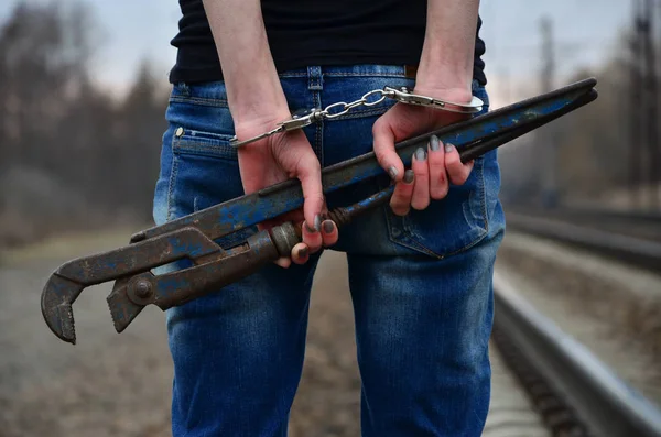 Дівчина в наручниках з трубним ключем на залізничній колії — стокове фото