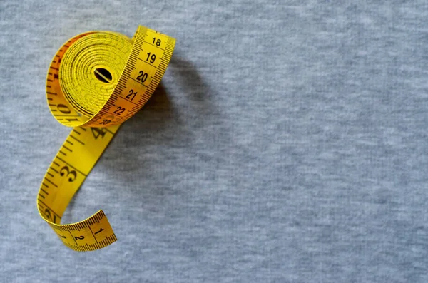Ruban à mesurer jaune repose sur un tissu tricoté gris — Photo